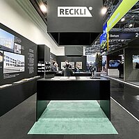 Green and black RECKLI exhibition stand at BAU 2023.
